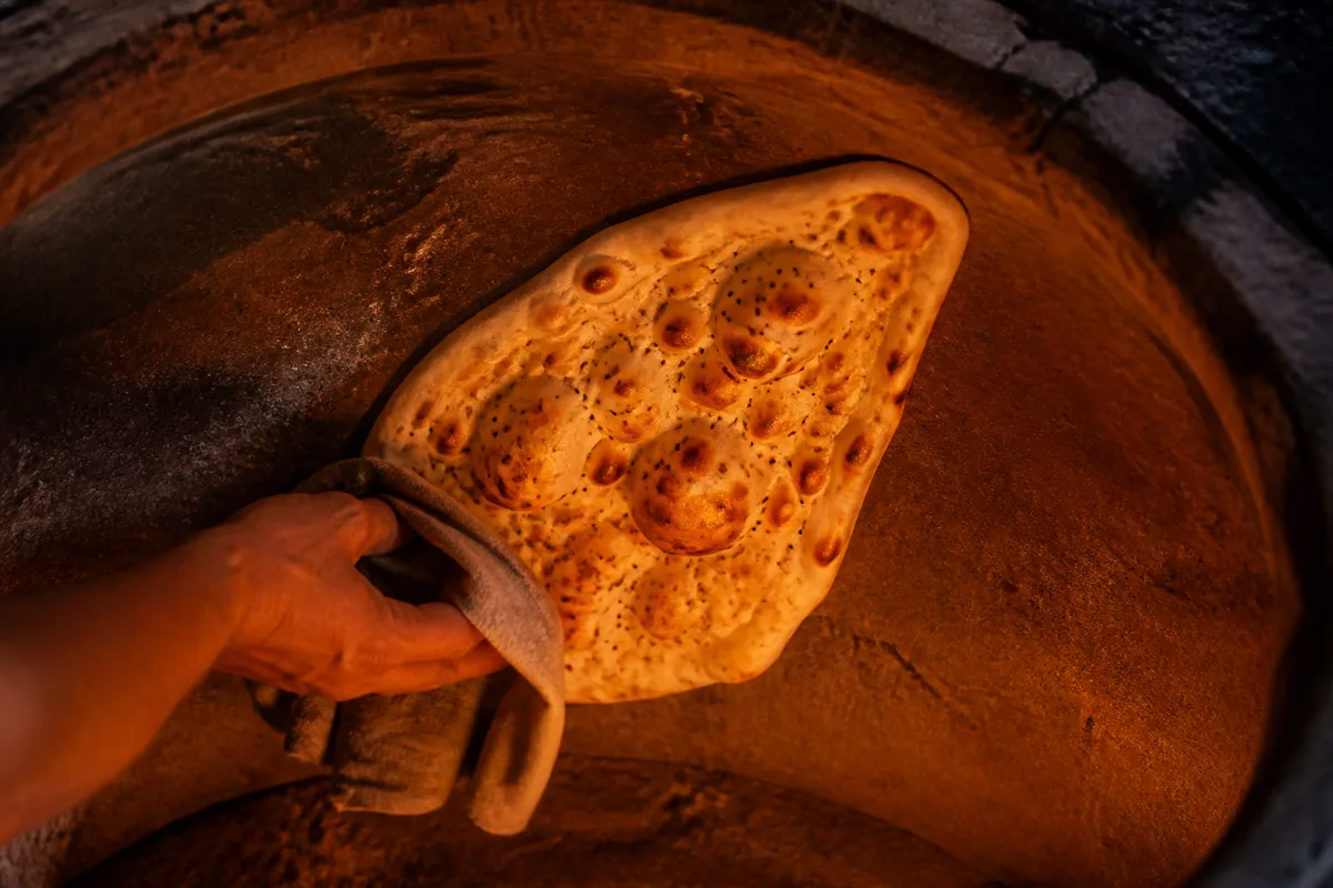 Pain plat doré collé sur la paroi intérieure brûlante d’un four traditionnel